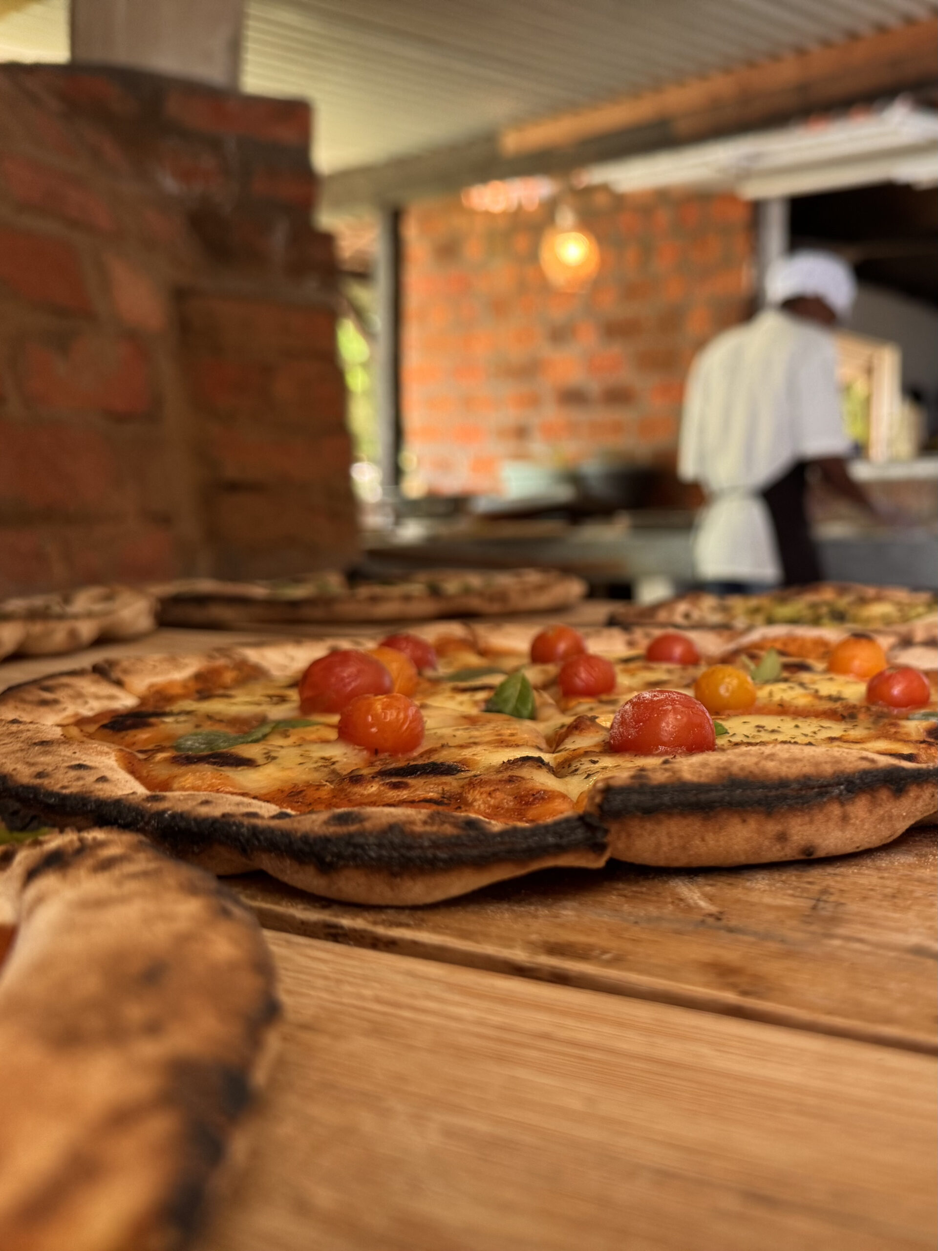 Eine Pizza Margherita bei Pizz'Aurora im Hochformat, mit dem Küchenchef im Hintergrund